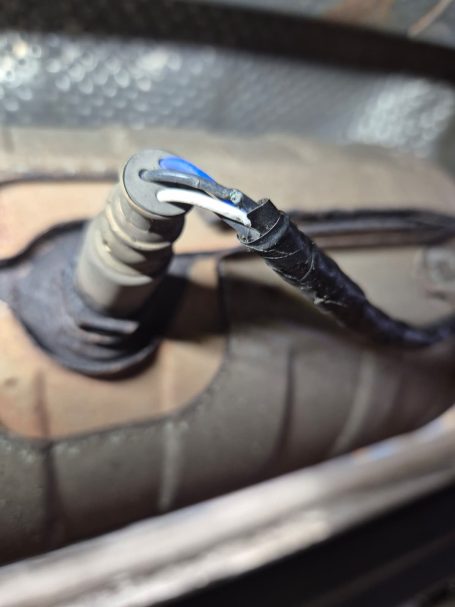 Close-up of a car's oxygen sensor showing wiring corroded.