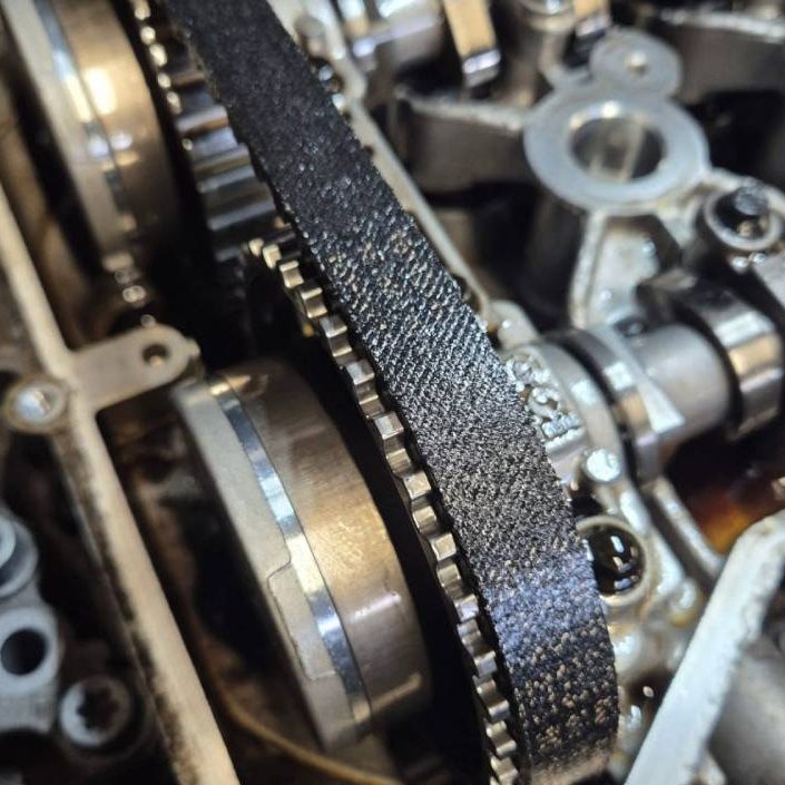 Overhead view of a 2015 Citroën C4 Cactus 1.2 PureTech engine with the top cover removed, showing a worn and cracked original wet timing bel